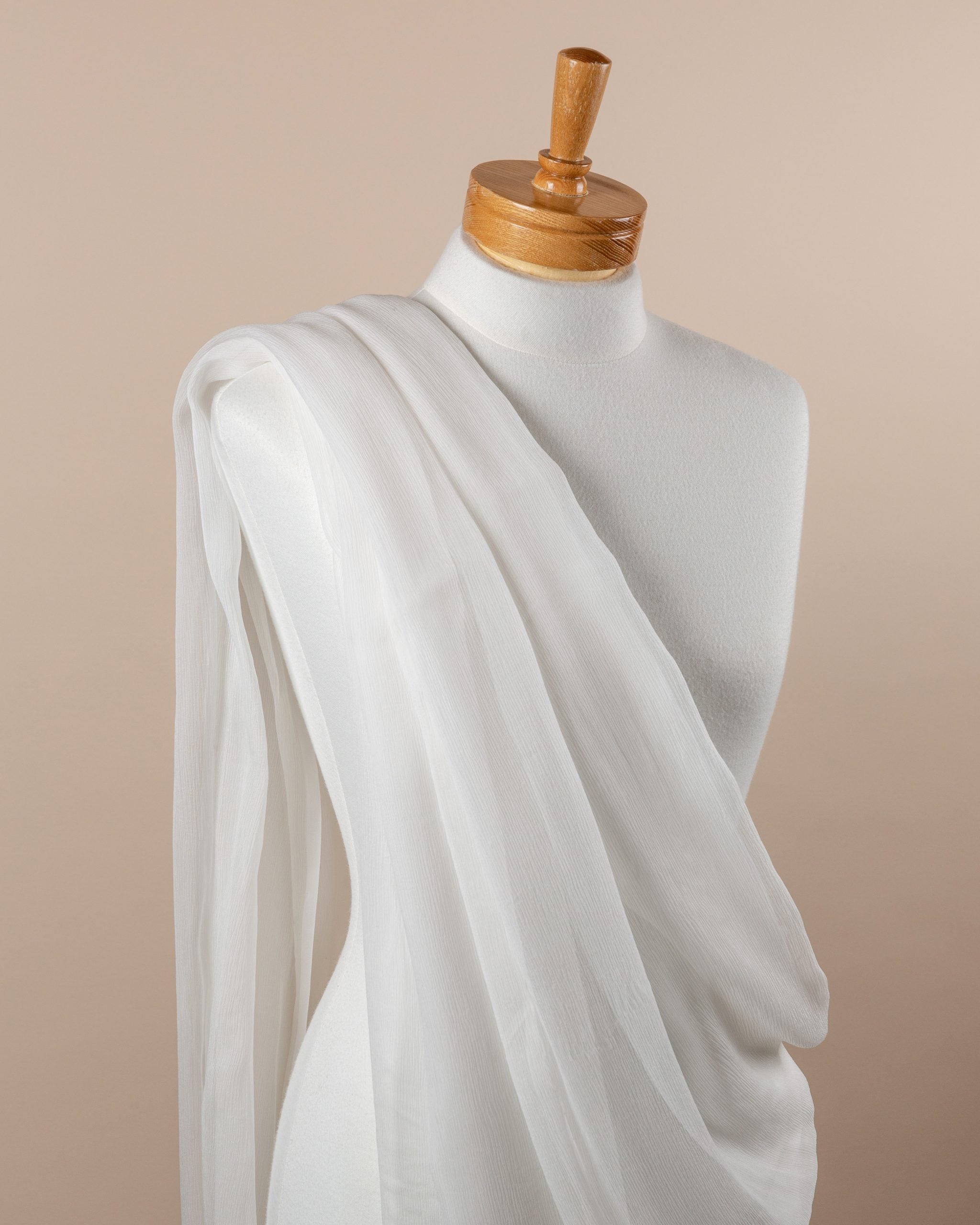 Mannequin draped with undyed silk crinkle chiffon fabric against a beige background