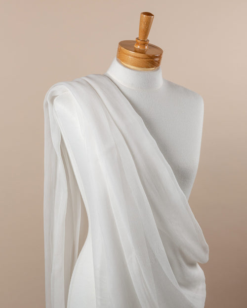 Mannequin draped with undyed silk crinkle chiffon fabric against a beige background