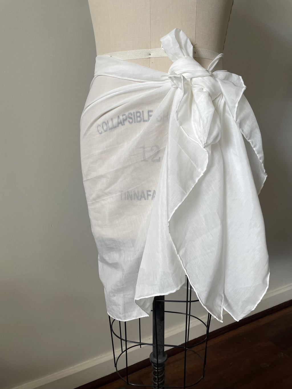 Undyed silk cotton voile sarong tied at the waist on a mannequin with text on a plain background