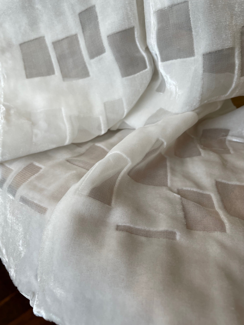Close-up of a textured white devore scarf with gray square patterns