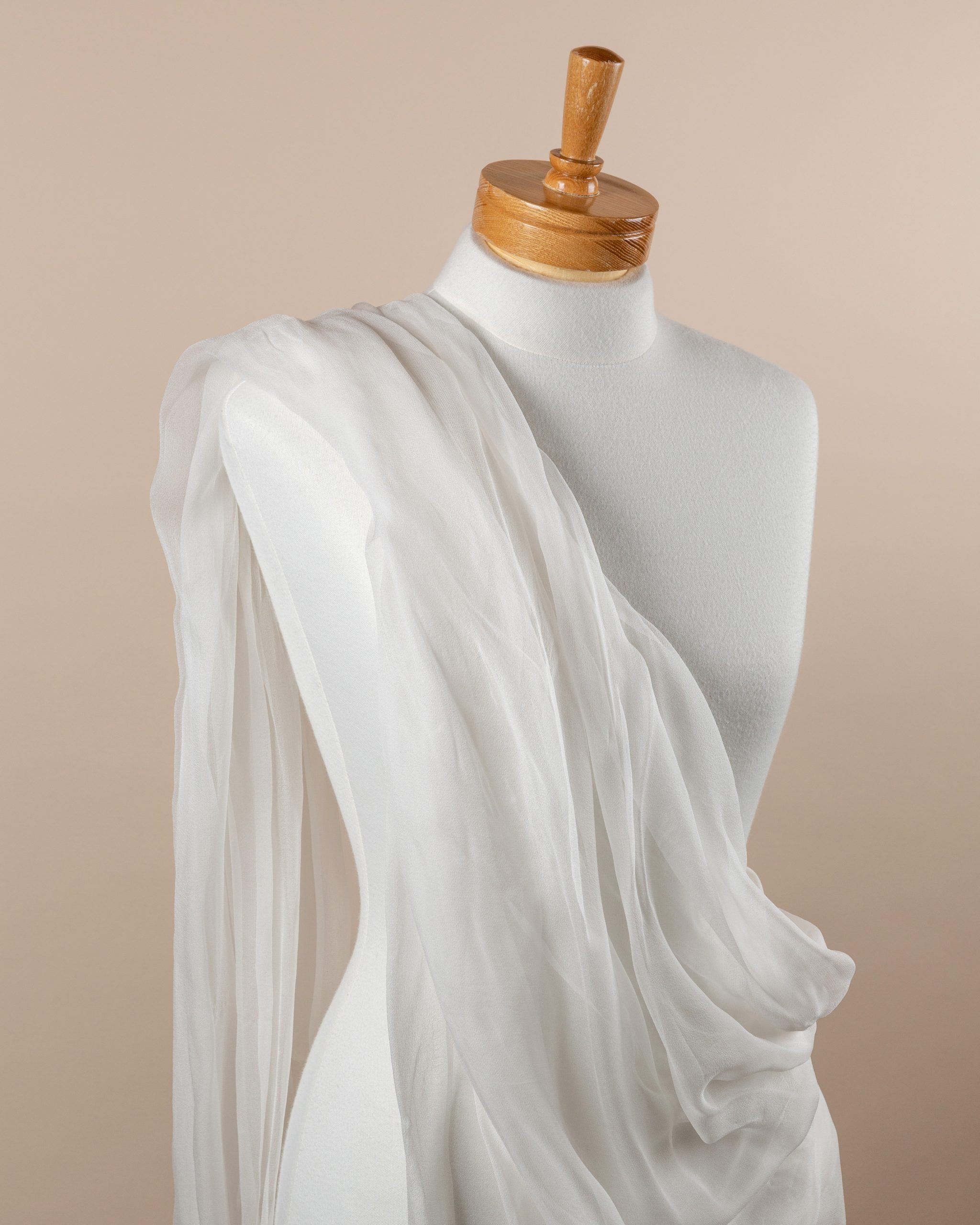 Undyed silk gauze white fabric draped over a mannequin on a beige background