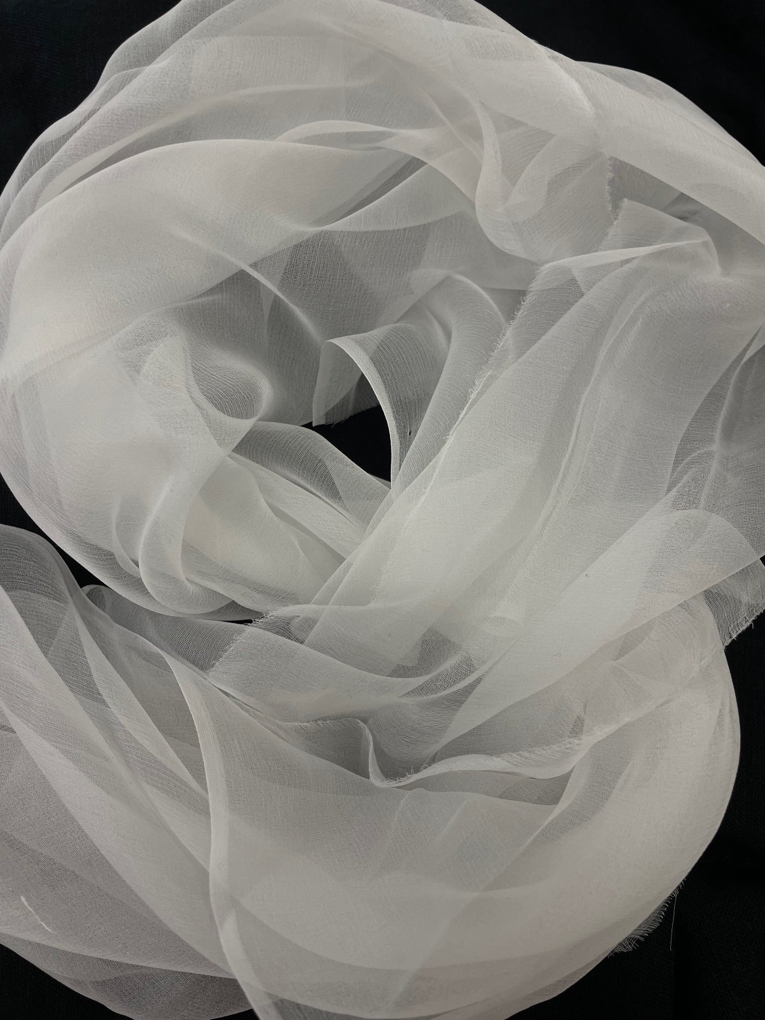 Undyed white silk gauze fabric in the shape of a rose on a black background