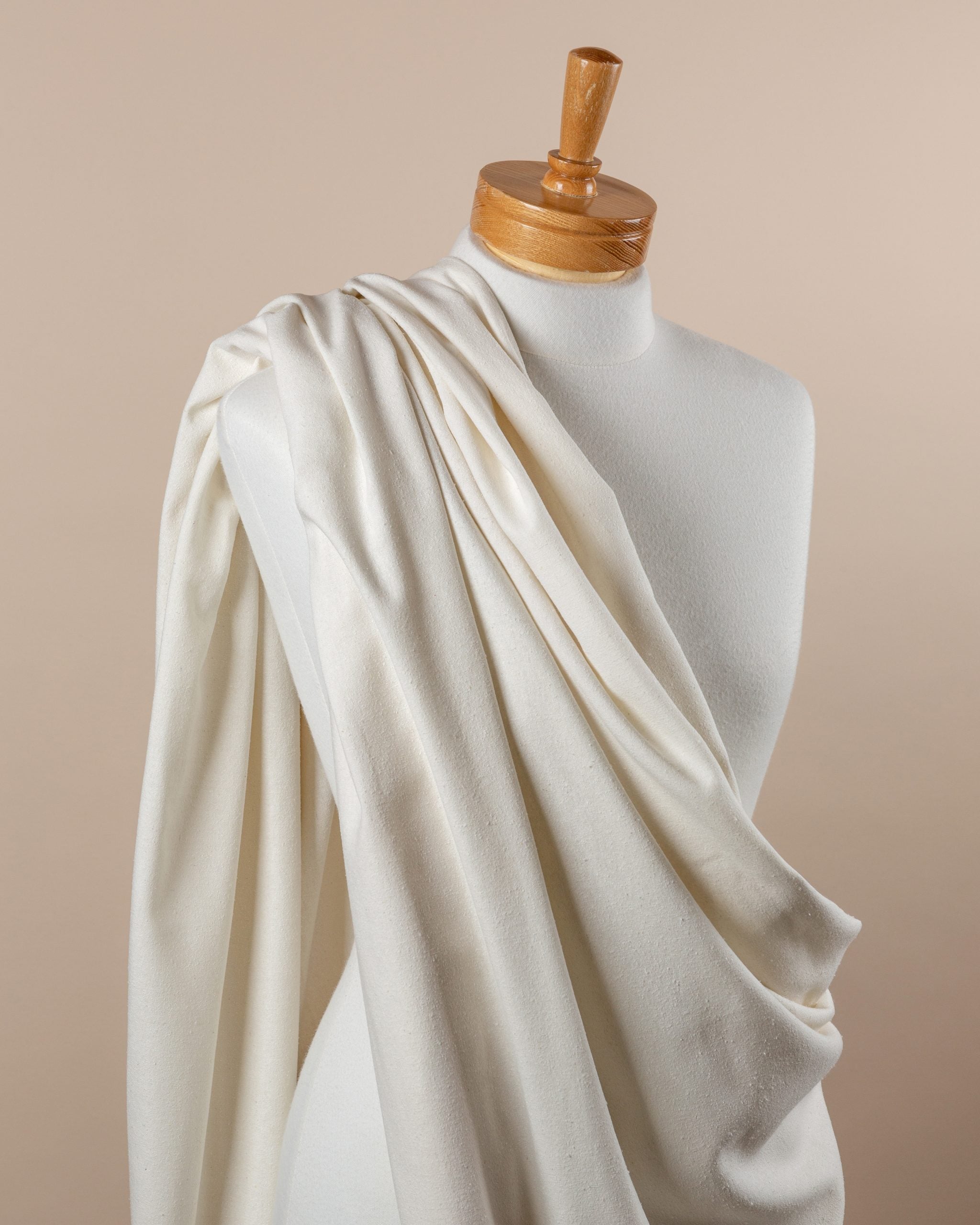 Mannequin draped with undyed silk noil  fabric against a beige background