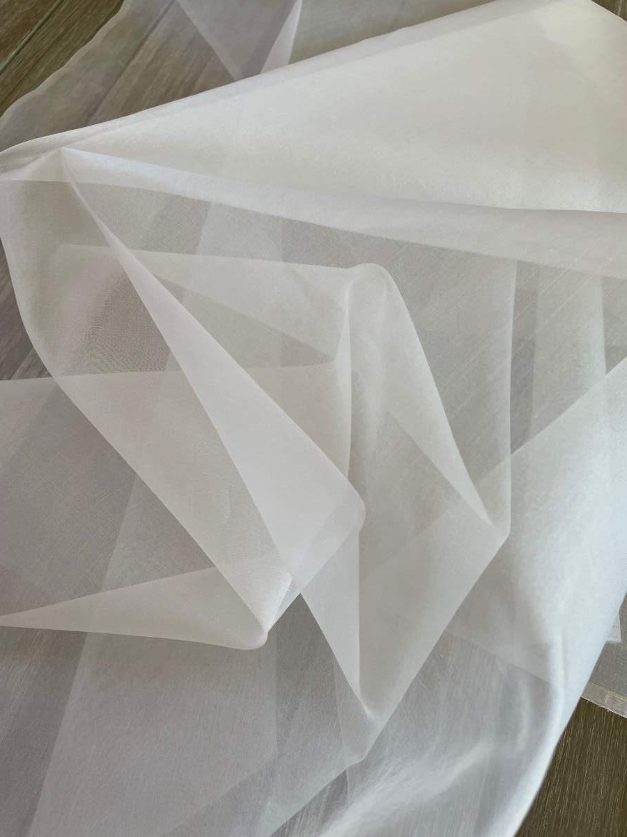 Undyed silk organza fabric with a crisp folds on a wooden surface