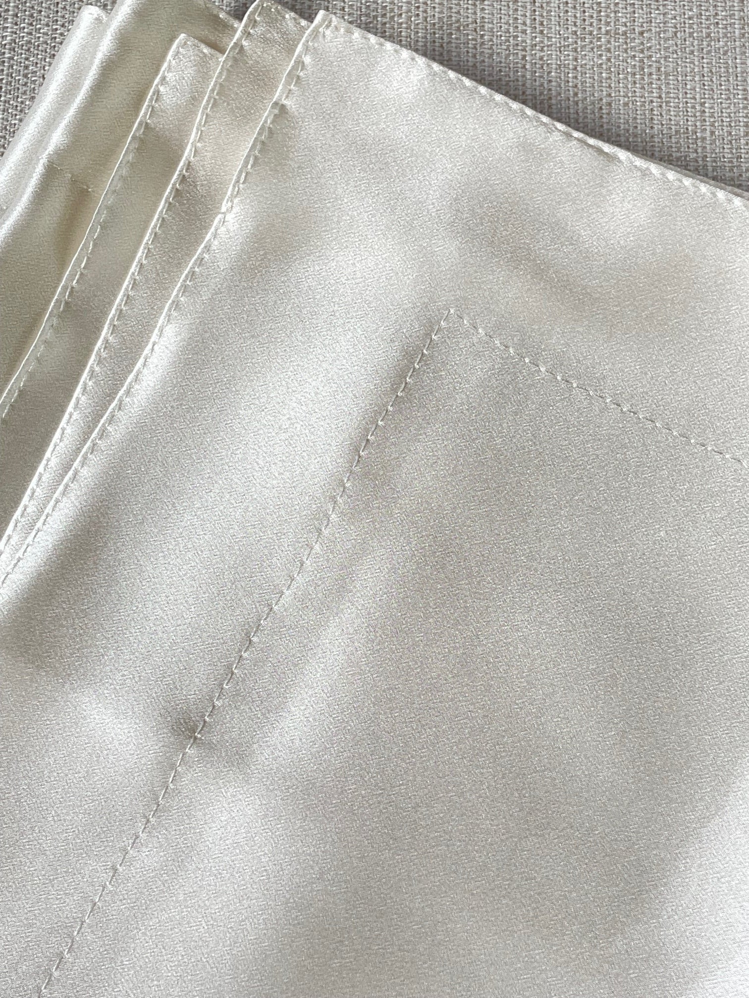 Close-up of folded undyed silk satin pillocase with a textured surface