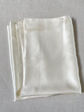 Undyed silk satin pillowcase folded on a gray surface