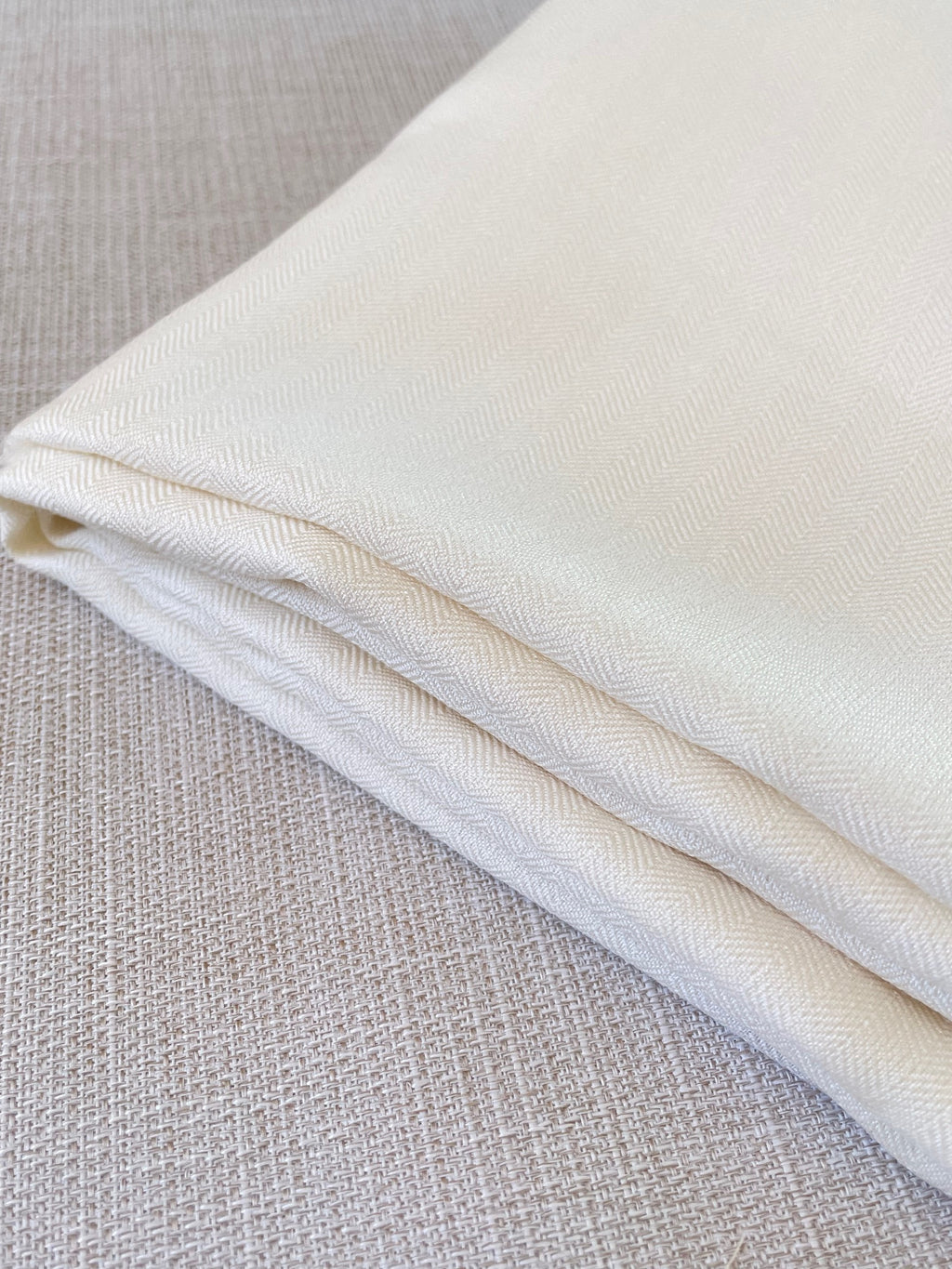 Close-up of undyed silk wool fabric on a textured gray background