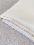 Close-up of undyed silk wool fabric on a textured gray background