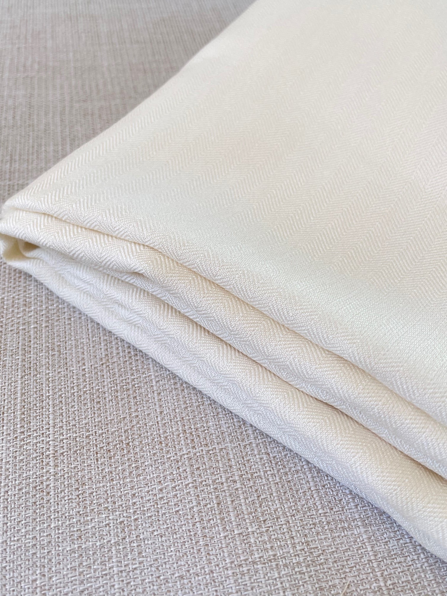 Close-up of undyed silk wool fabric on a textured gray background