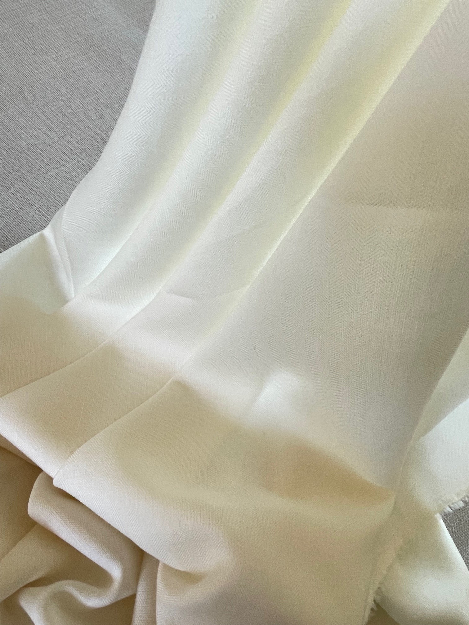 Close-up of undyed silk wool fabric with folds on a gray background