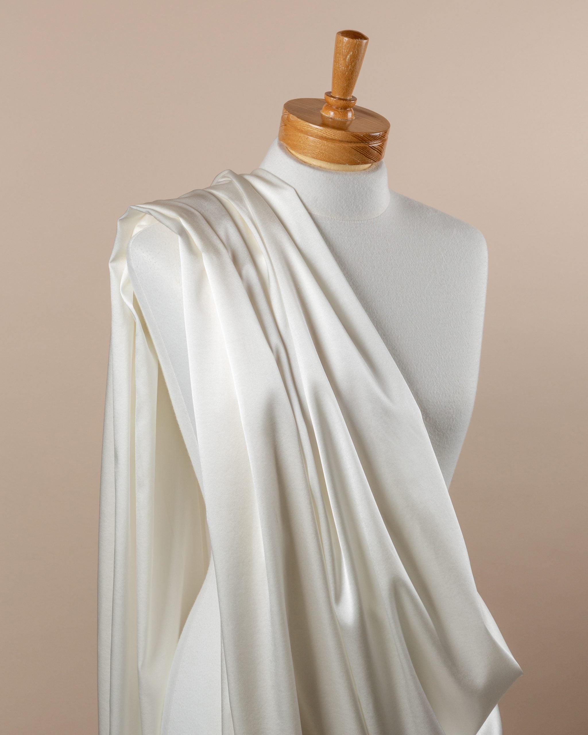 Undyed stretch satin silk fabric draped over a mannequin on a beige background