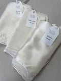 Folded Undyed silk scarves with tags on a gray background
