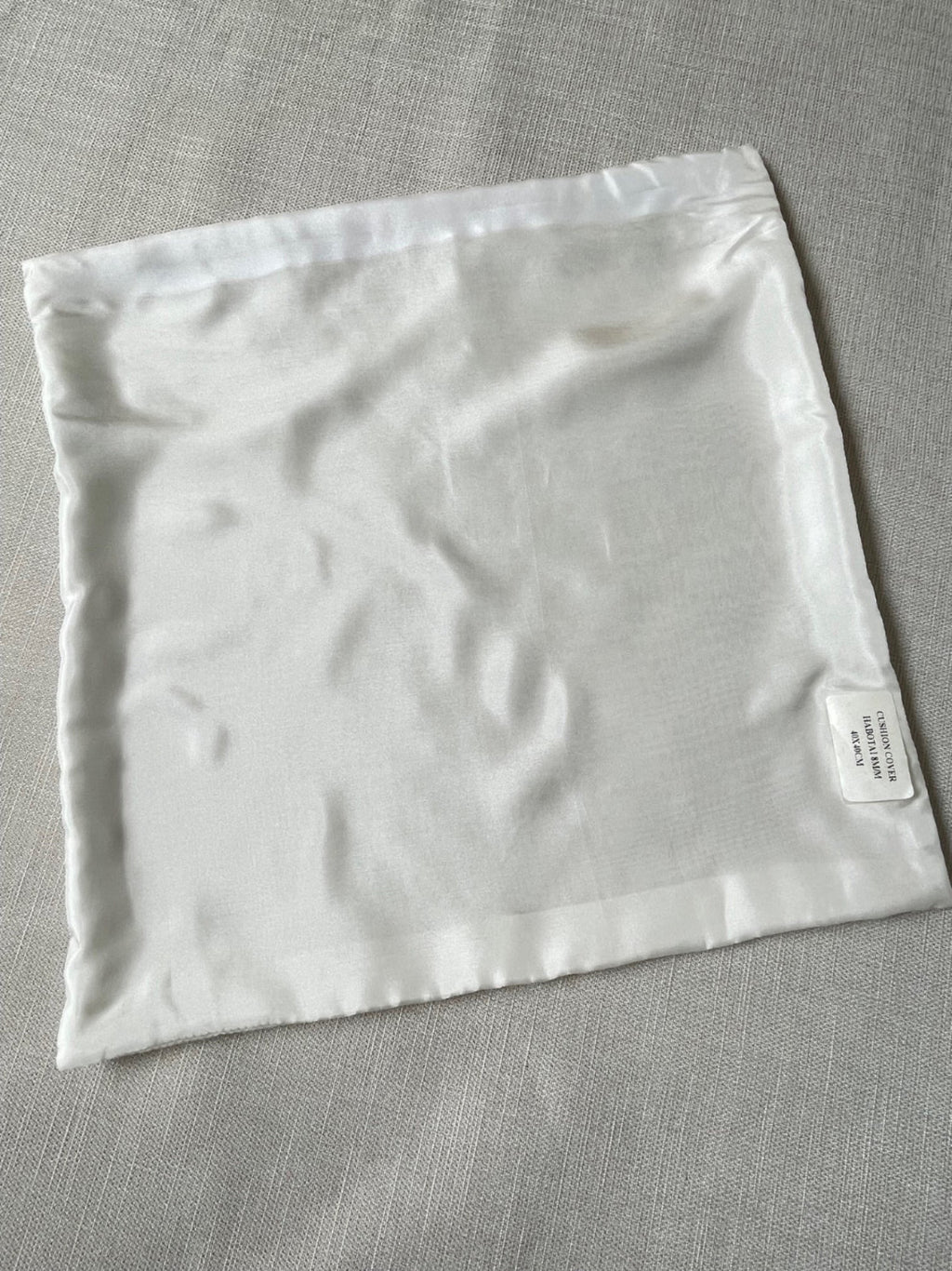 Undyed white Habutai silk cushion cover on a gray fabric background