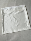 Undyed white Habutai silk cushion cover on a gray fabric background