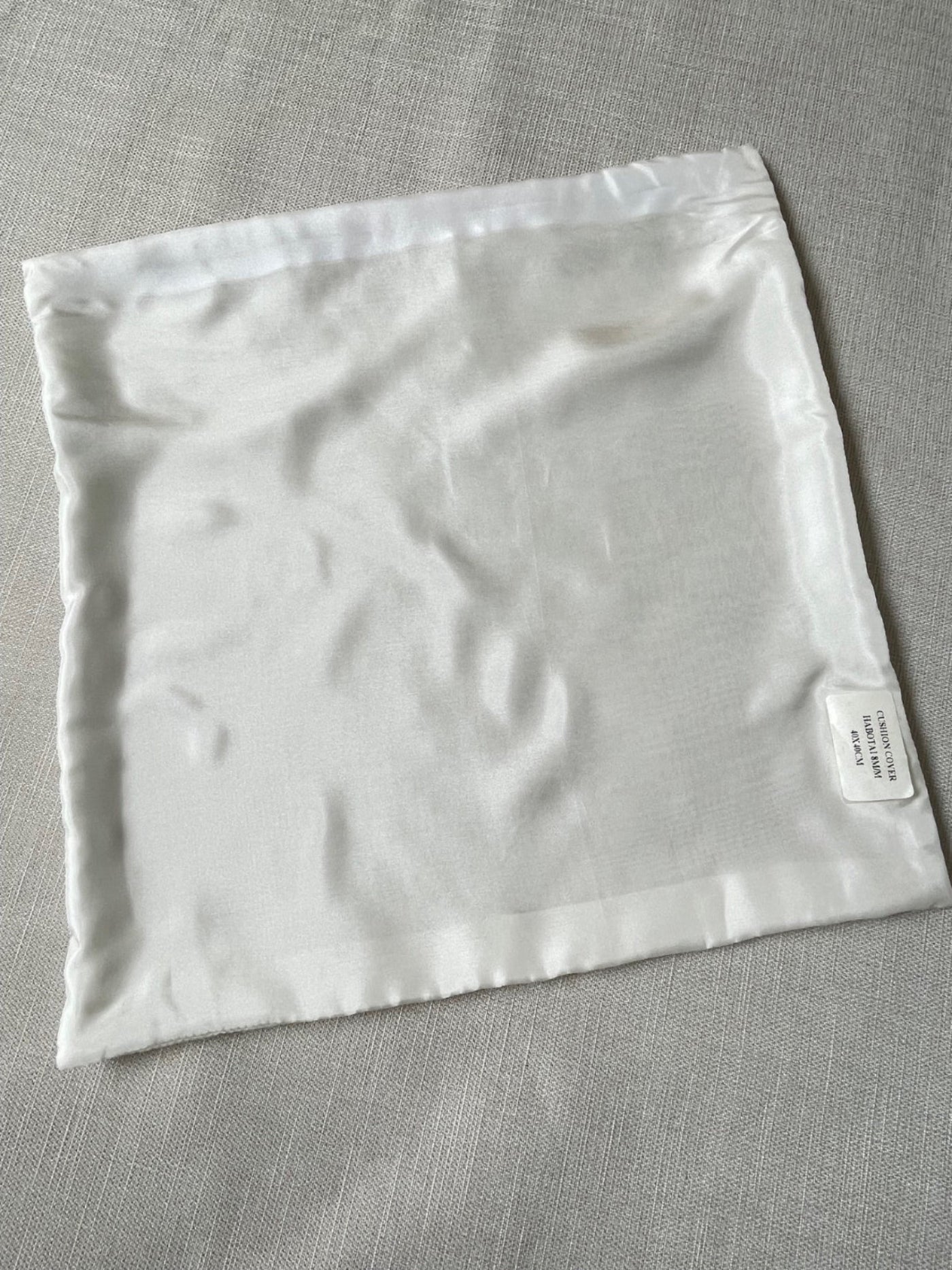Undyed white Habutai silk cushion cover on a gray fabric background