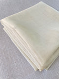 Folded undyed wool gauze fabric on a textured gray surface