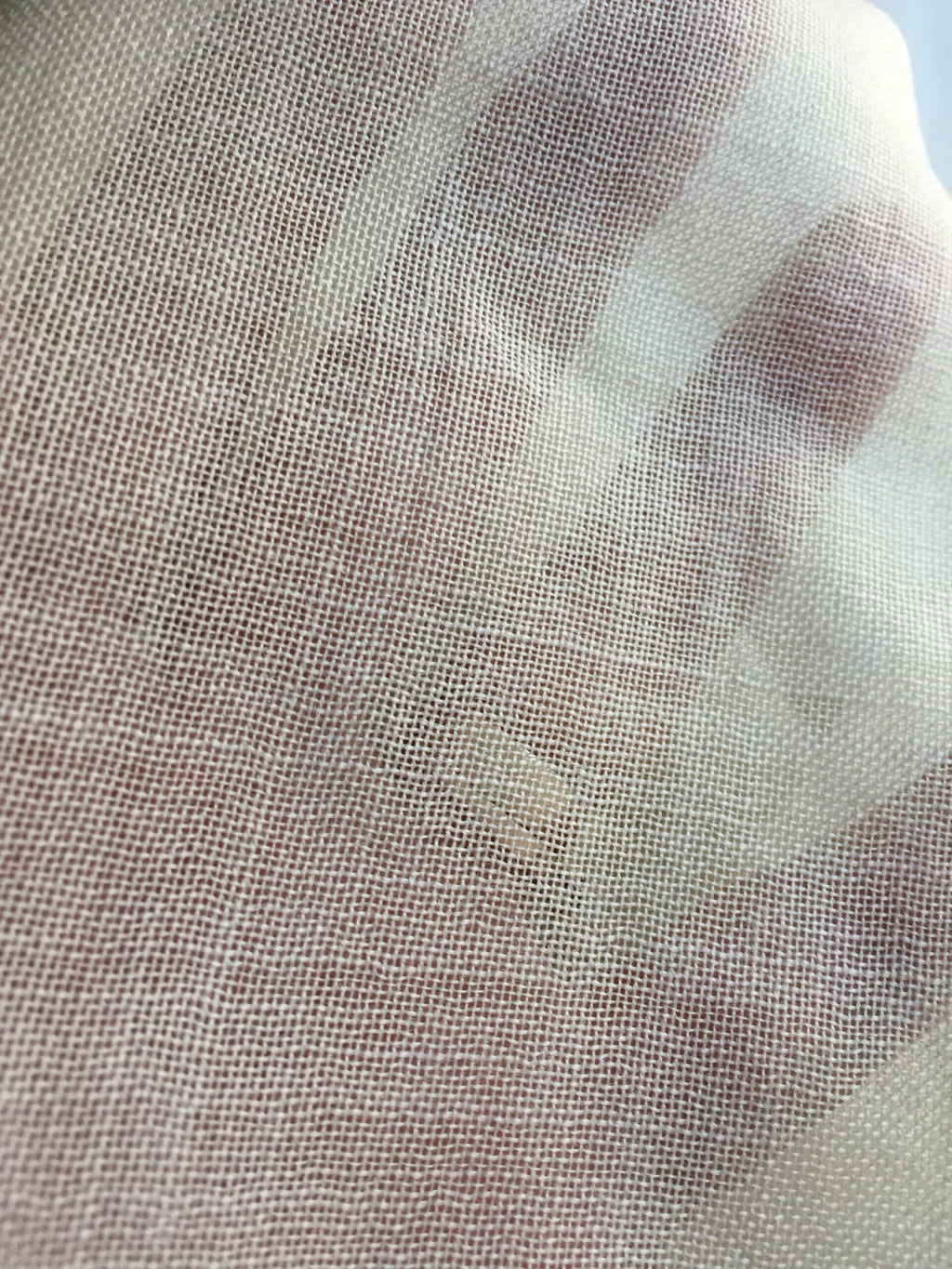 Close-up of a texture and sheerness of undyed wool gauze fabric with a neutral color palette