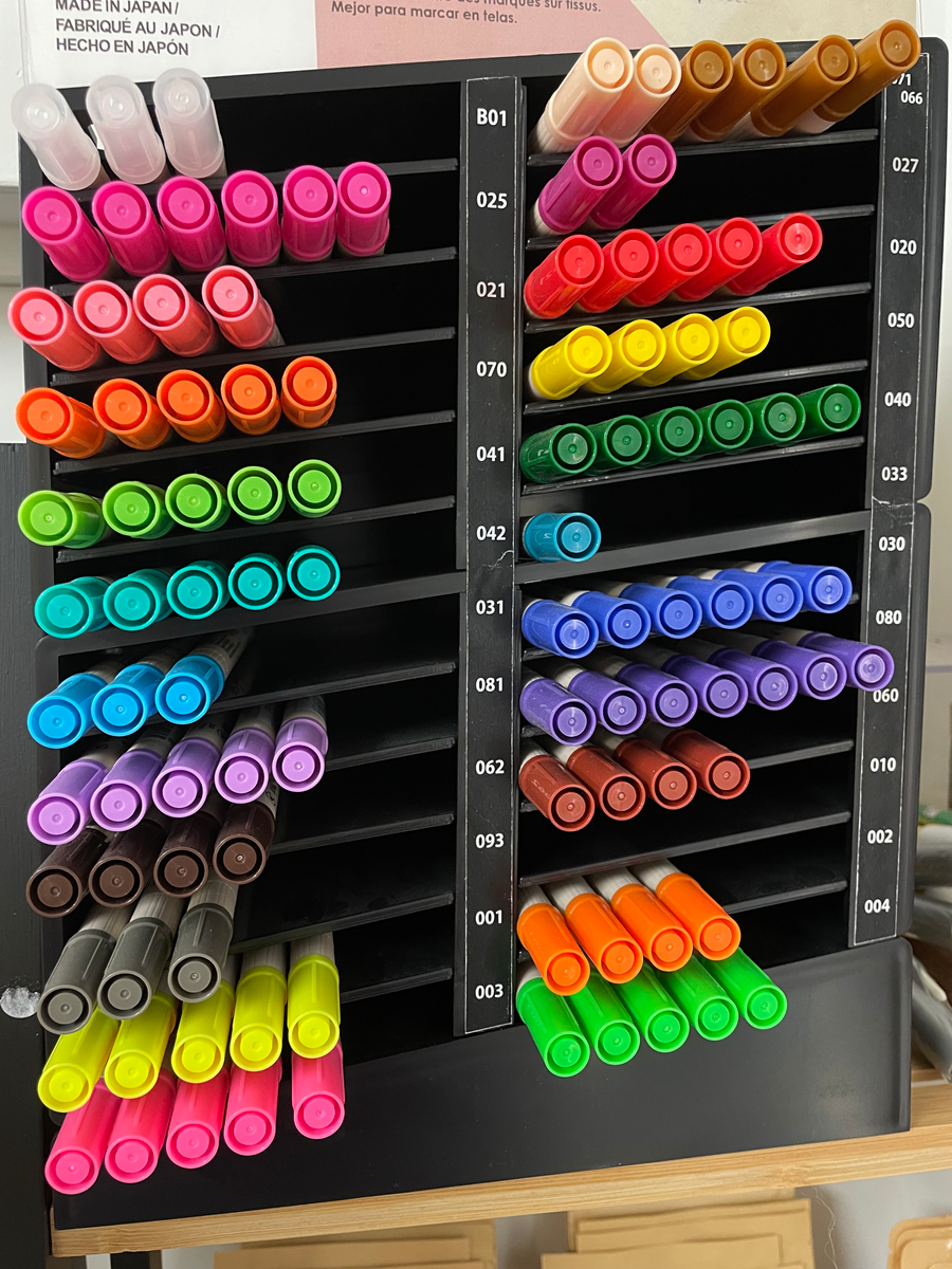 Colorful markers organized in a black storage case on a wooden surface.